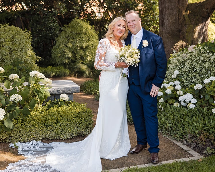 A bride and groom embrace in the garden at Clontarf Castle Wedding Venue in Dublin.